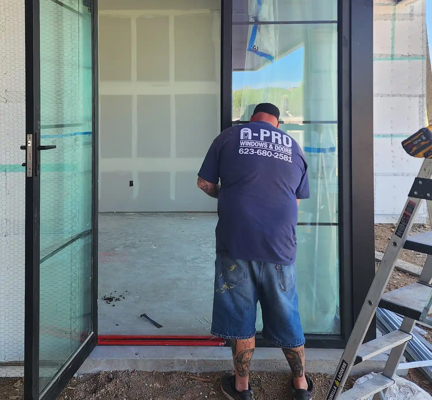 A Pro Windows and Doors technician installing glass door at a construction site.