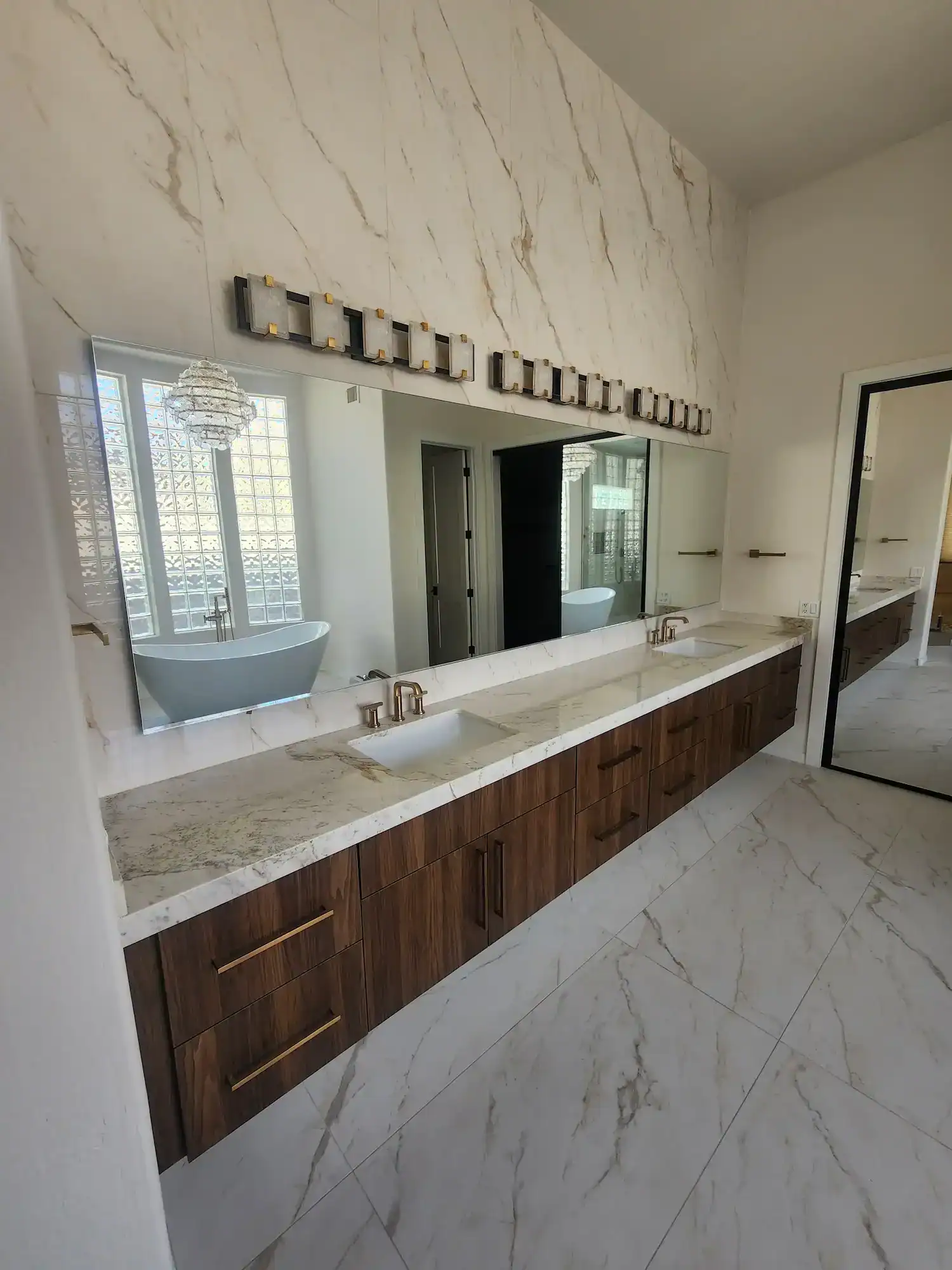 Modern bathroom with marble and wooden details featuring a custom cut mirror installed by A Pro Windows & Doors.