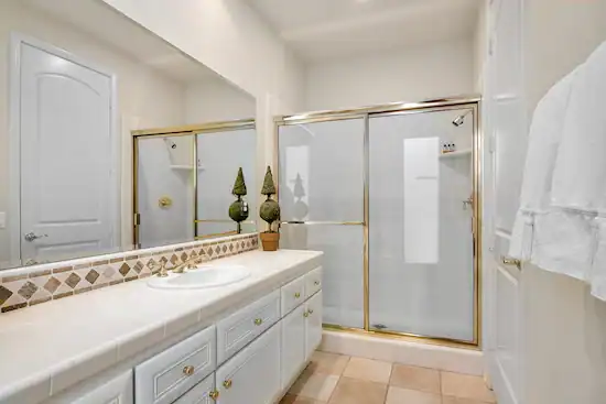 Modern bathroom with a gold, framed shower enclosure, an example of the kind of shower enclosures A Pro Windows & Doors can do.