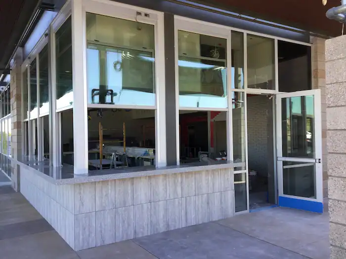 After photo showing a completed commercial project for a local restaurant In Phoenix done by A Pro Windows & Doors, showing off a corner section with pass through windows and a marble bar.