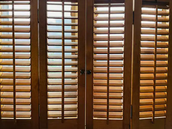 Sunlight through wooden window shutters indoors.